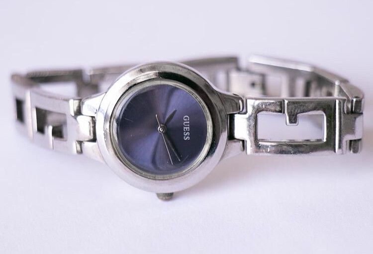 Vintage Blue Dial Guess Ladies Watch  With a round silver-tone case and an elegant silver-tone bracelet, this vintage blue-dial Guess ladies watch will definitely get noticed on the wrist. The watch has a minimalist design, yet the navy blue dial adds an