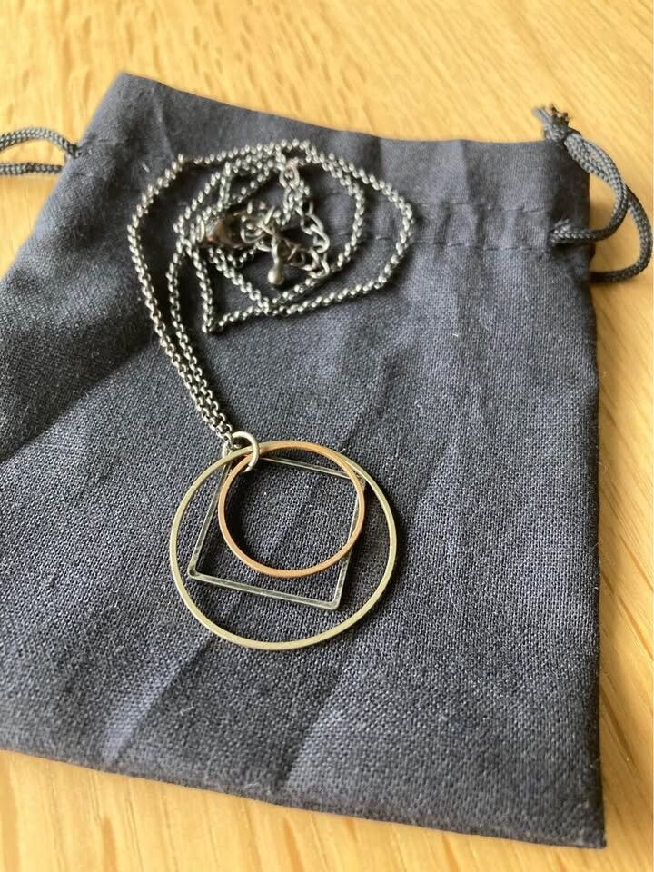 Tri-colour geometric pendant necklace on gun metal tone adjustable length chain. With presentation pouch.