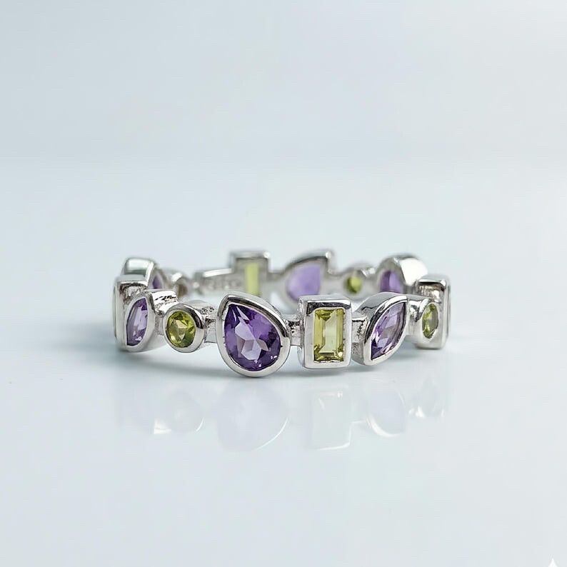 ✨ Genuine Amethyst & Peridot Sterling Silver Ring ✨  A little piece of wearable art. This stunning eternity-style ring features genuine amethyst and genuine peridot gemstones in a mix of pear, marquise, round and emerald cuts, creating a colourful mosaic 